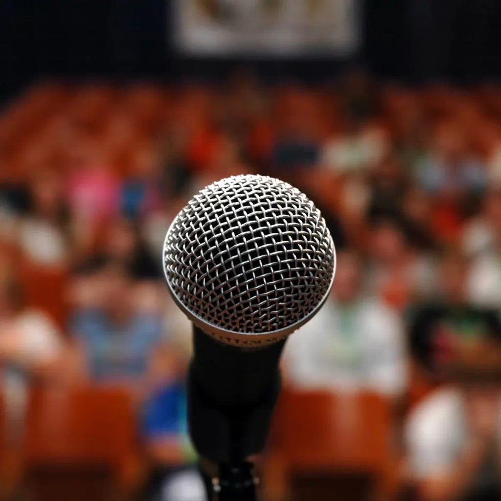 Closeup of microphone in front of large audience.
